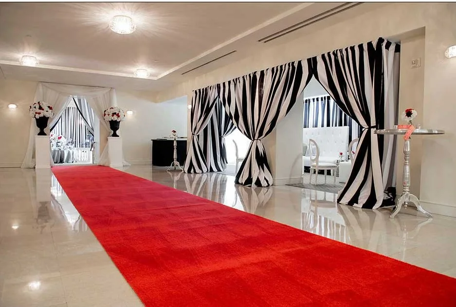 a-red-carpet-runner-in-an-elegant-white-venue-with-black-and-white-striped-drape-backdrops-and-floral-arrangements